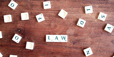 Scrabble letters forming the word 'LAW'