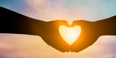 Silhouette of two hands forming a heart symbol